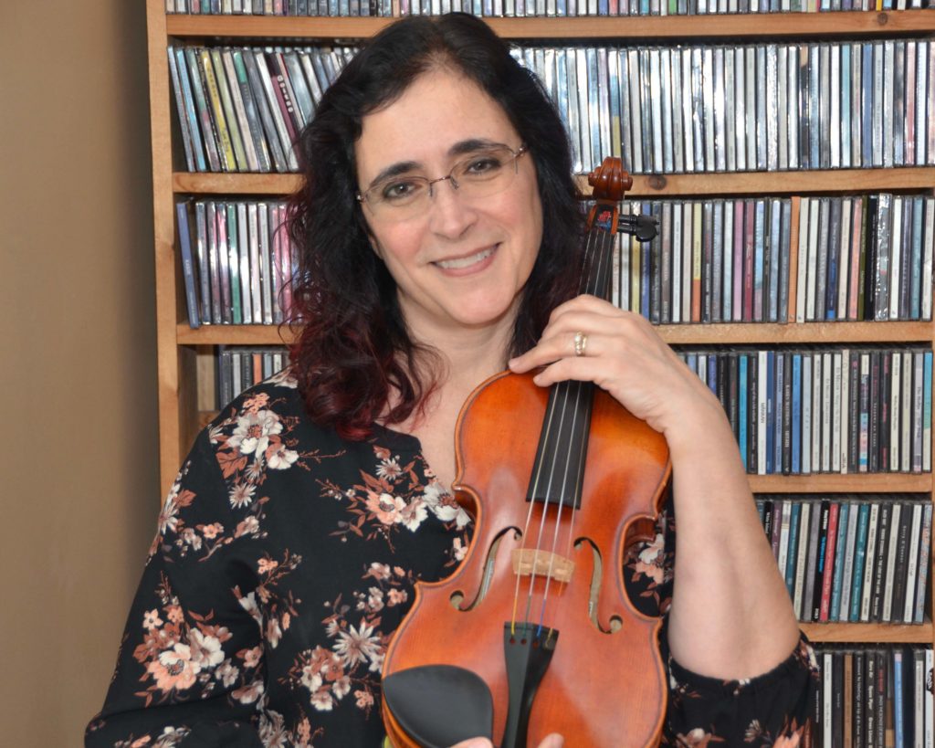 Karen posing with violin in front of CD collection